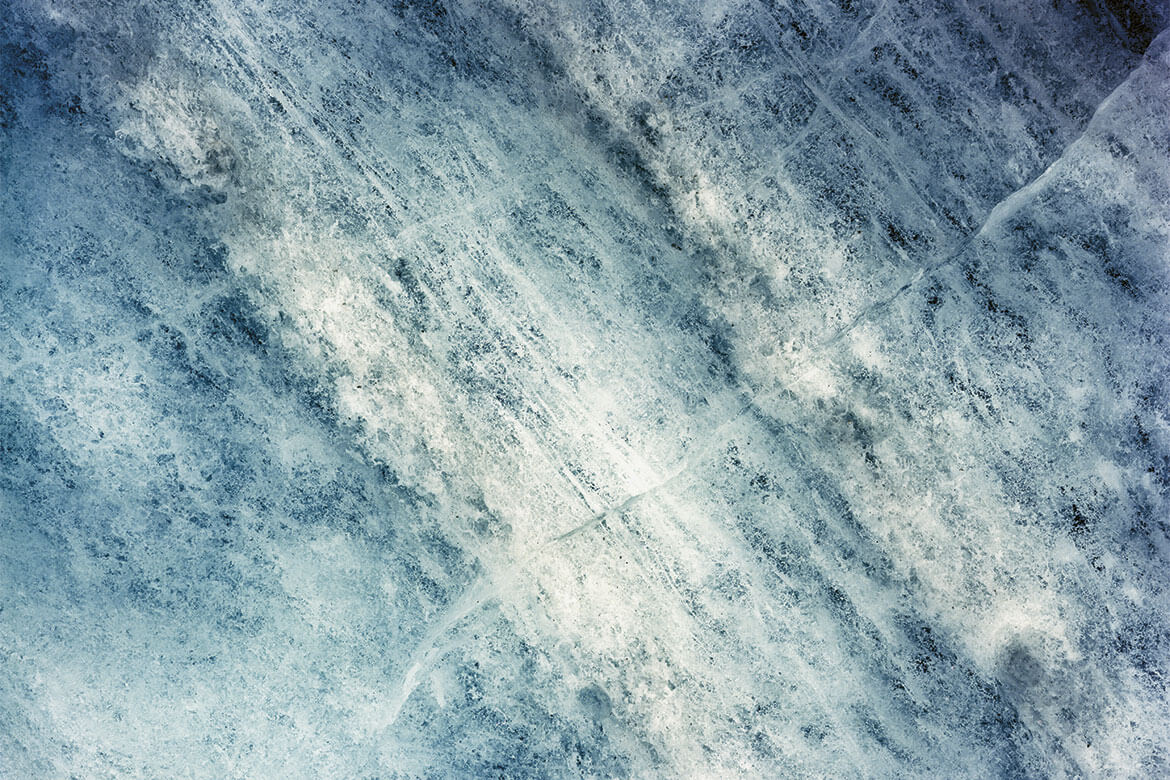 Zahlreiche Luftbläschen, schräg verlaufende Risse: Die Komplexität der Eismasse des Morteratschgletschers bei Pontresina (GR) zeigt sich im Detail. | Bild: «Glacier Fabric», Matthias Vollmer. Bemerkung: Die Fotografie wurde um 90 Grad nach rechts gekippt.